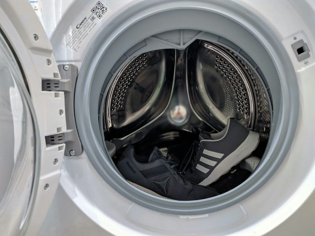 why is my washing machine shaking, Person inspecting a washing machine's leveling feet to stop excessive shaking.